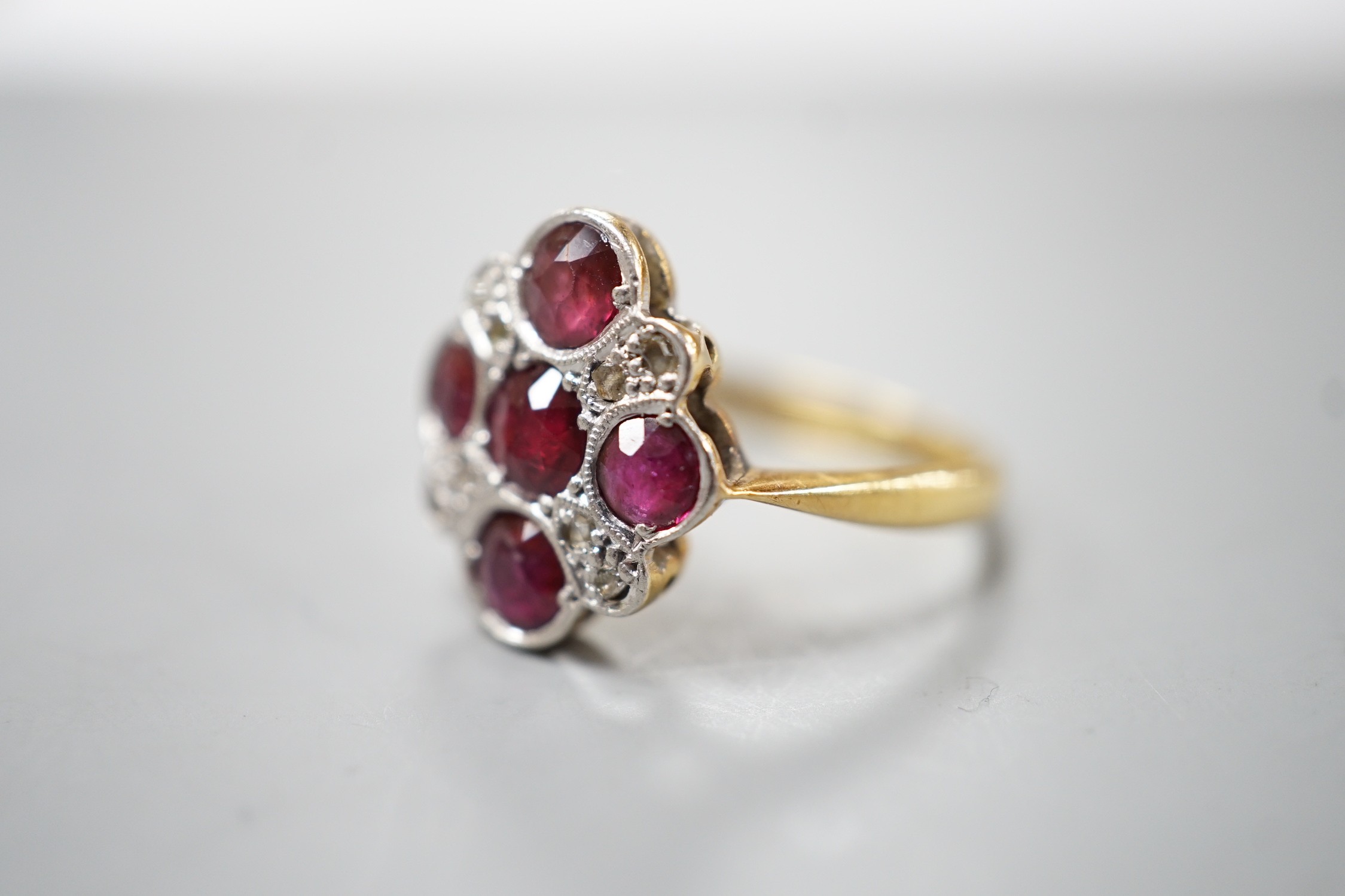 A 1920's 18ct and plat and five stone ruby set quatrefoil shaped ring, with diamond chip spacers, size L, gross weight 3.5 grams.